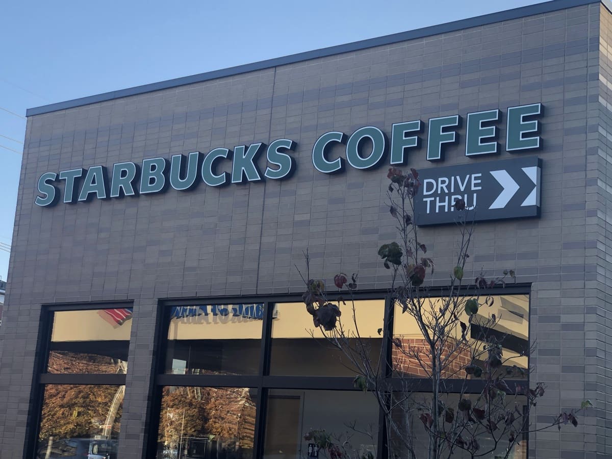 A starbucks coffee store with a sign in front of it.