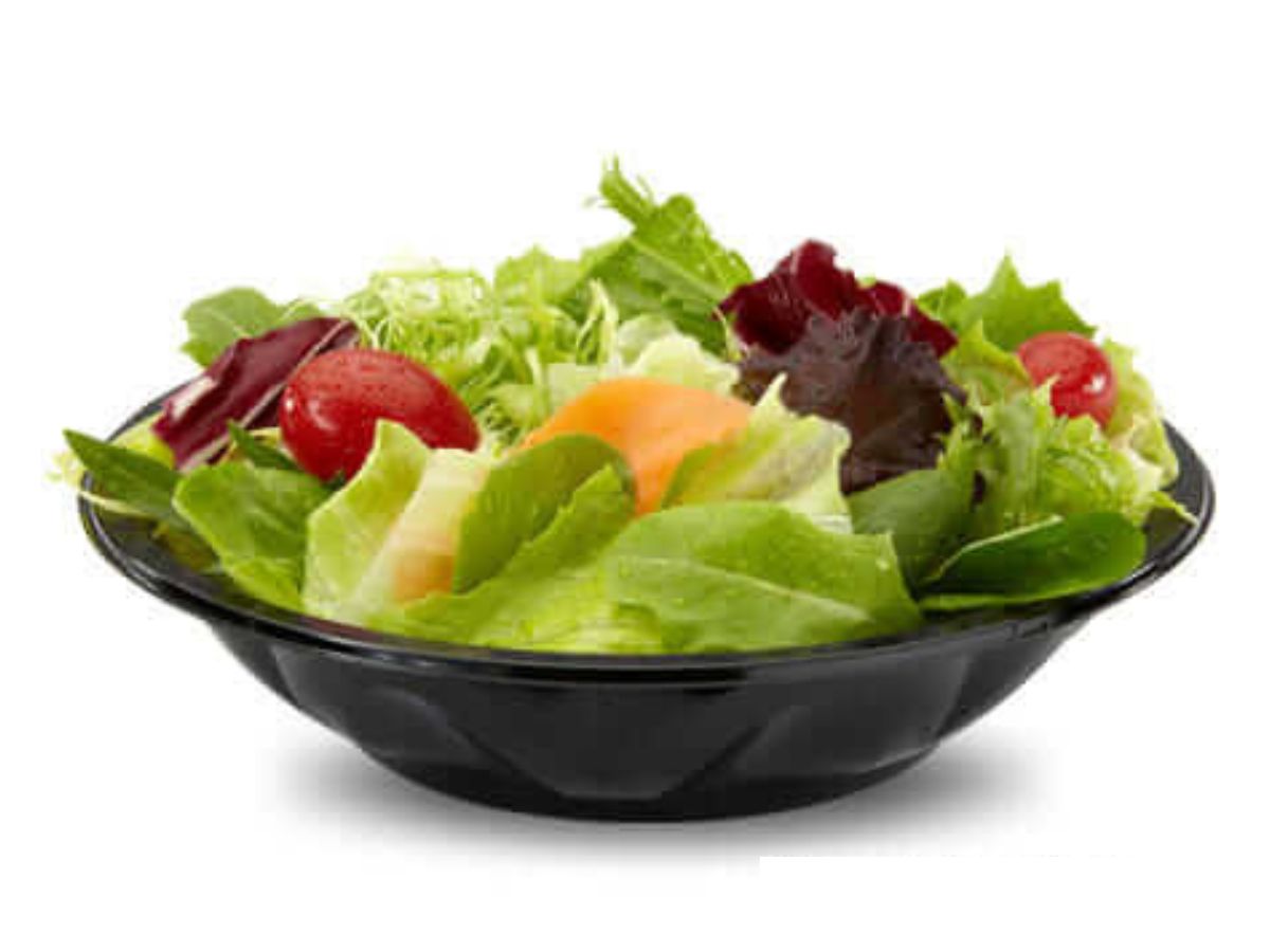A healthy salad served in a black bowl on a white background at McDonald's.