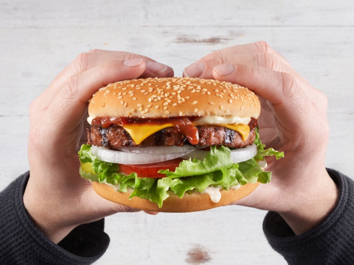 A person holding a fast food hamburger.