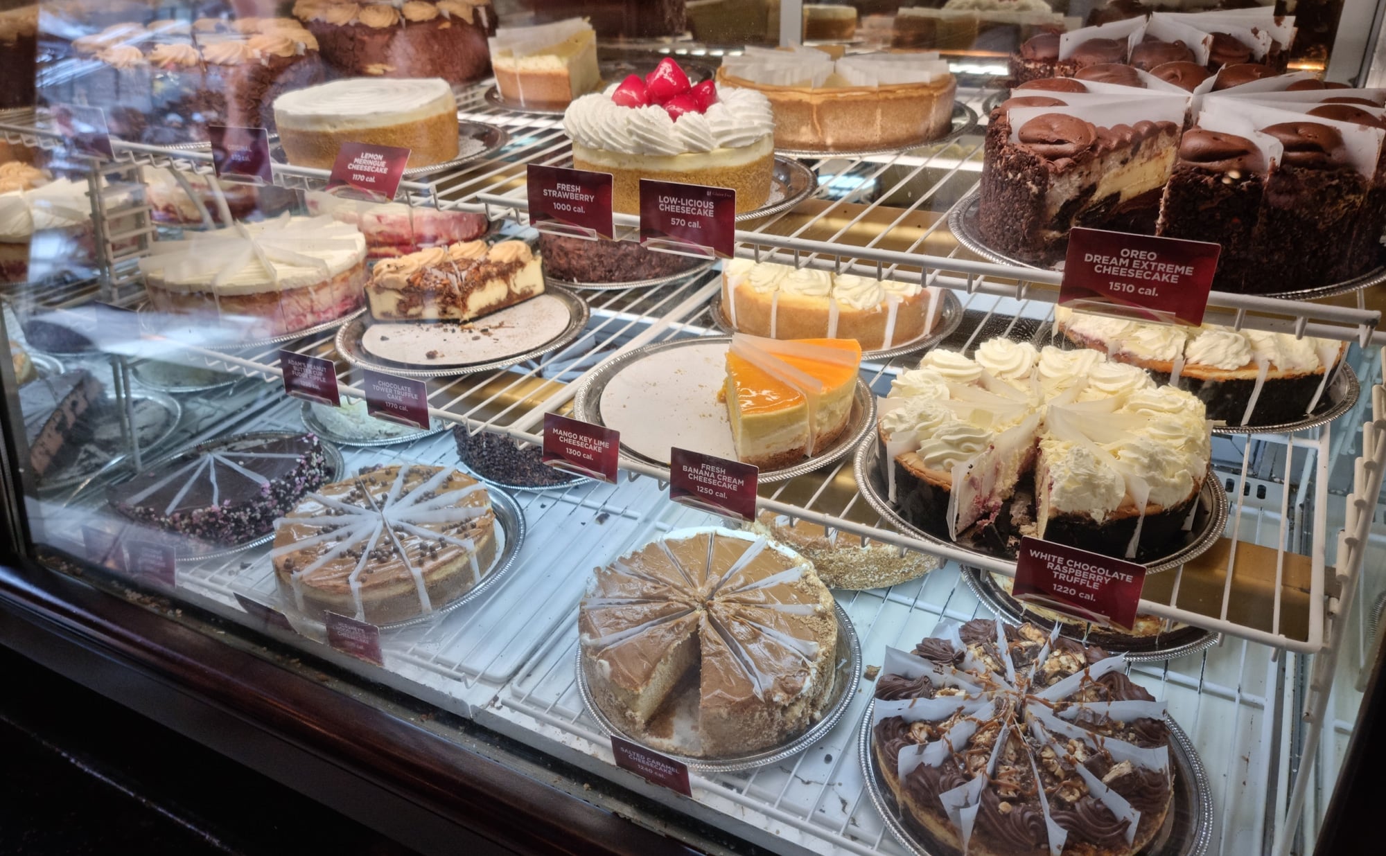 A display of cakes and pastries in a glass case.