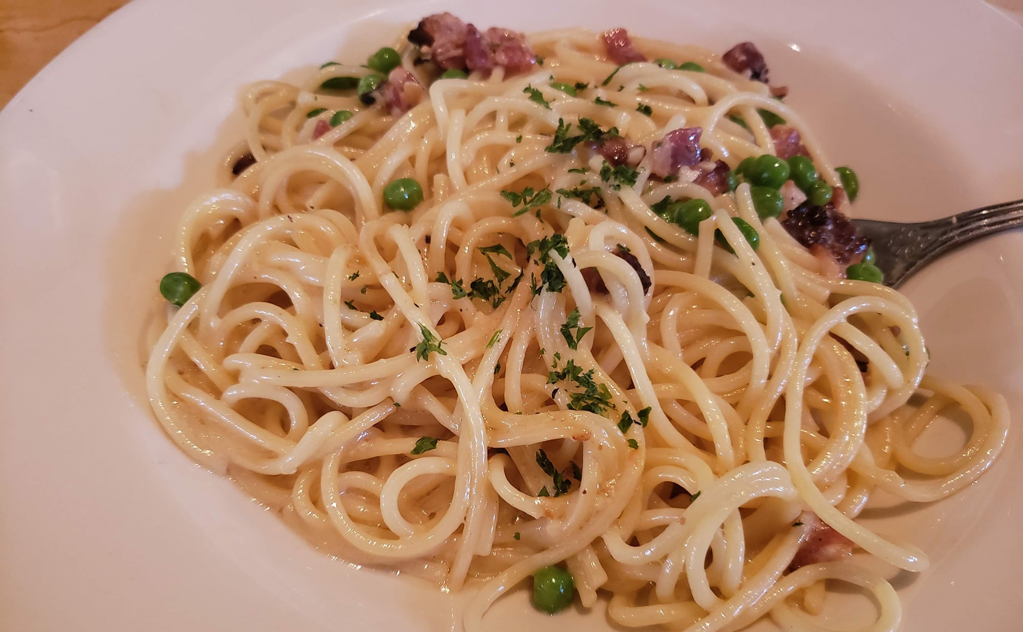 A plate of pasta with peas and bacon.
