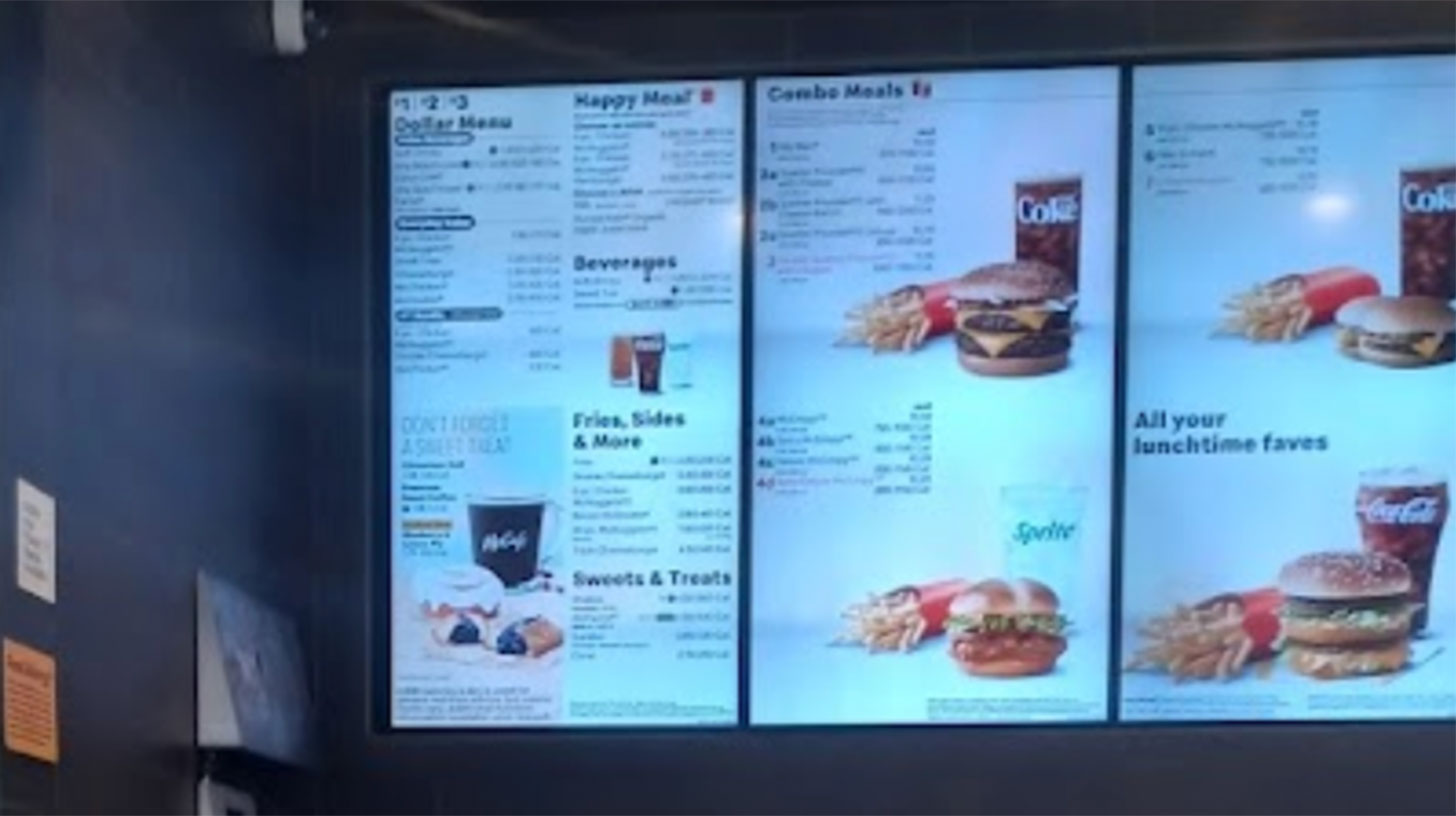A McDonald's menu, displaying prices, is shown on a large screen.