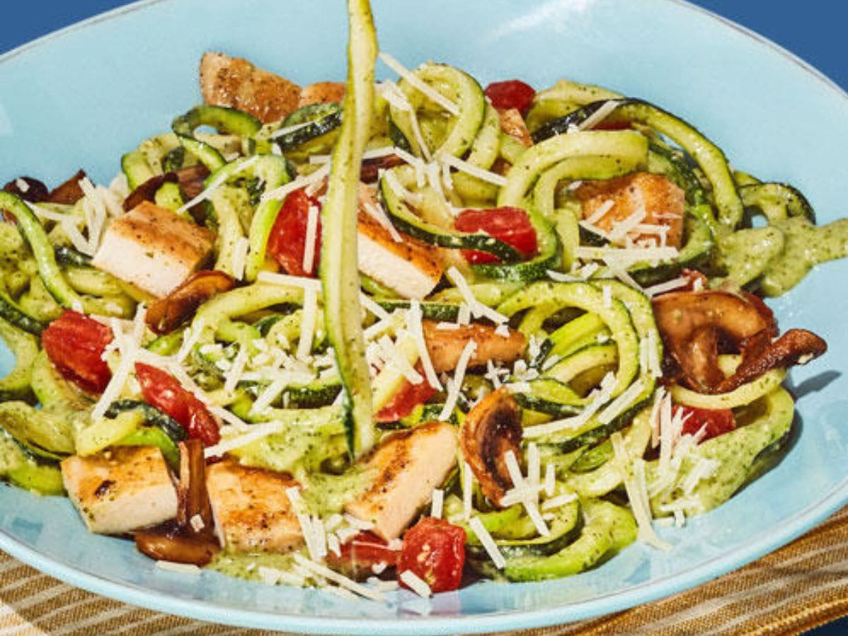 A bowl of cheap and healthy zucchini noodles with chicken, tomatoes and mushrooms