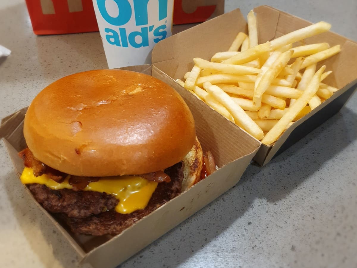 Mcdonald's burger with fries in a cardboard box.