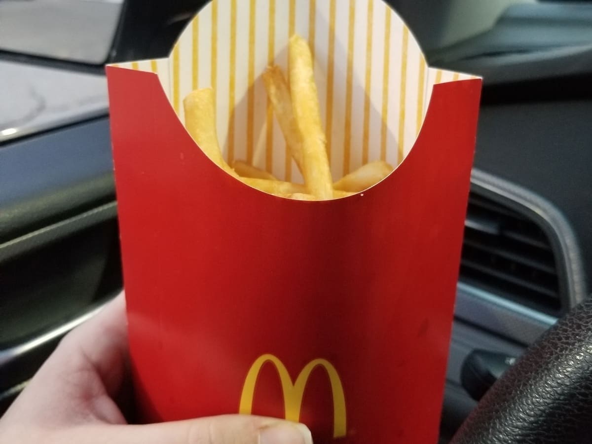 A person holding a mcdonald's bag of french fries.
